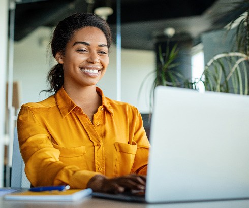 Woman smiling while working on laptop