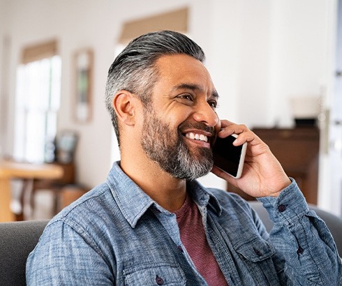 Man smiling while talking on phone at home