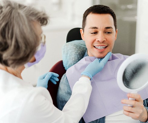 Man smiling at reflection in mirror with dentist