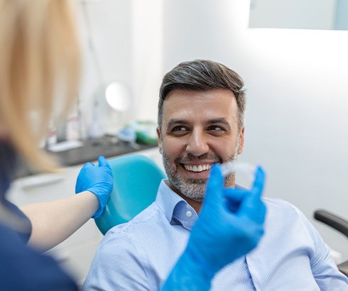 Patient smiling at dentist holding clear aligner