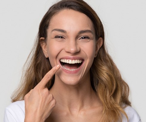 Happy woman pointing at her well-aligned teeth